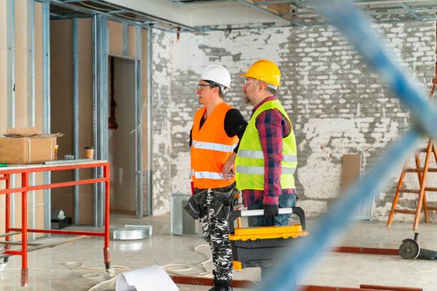 two adult workers with protective clothes looking at the construction area