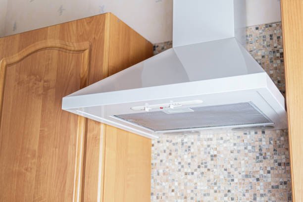 Ceiling metal white cooker hood above the kitchen stove. Modern kitchen appliances. A device for removing the smell of cooking food and tobacco smoke from the air.