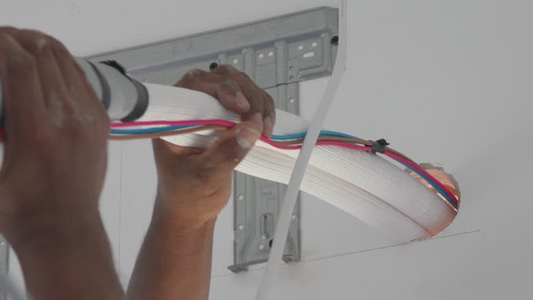 4K footage Close-up of technician hands installing insulated copper pipes and electrical wires for air conditioner unit on wall, Home repair and maintenance services.